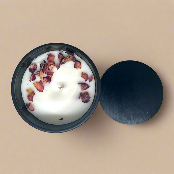 Soy wax candle decorated with rose petals in black concrete jar and black lid against a beige minimalist backdrop.