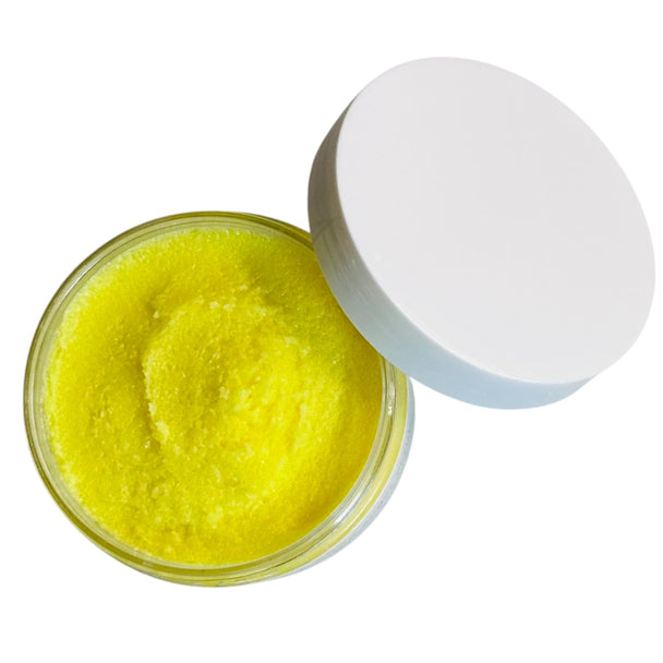 Close-up of natural brightening turmeric scrub in a biodegradable clear jar on a vibrant white background, showcasing its rich yellow color from organic turmeric and natural ingredients.