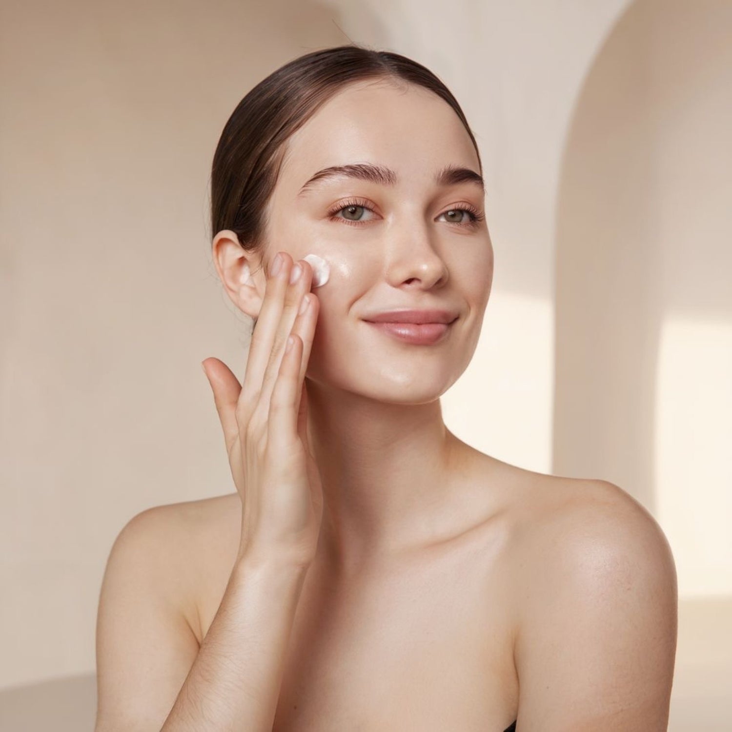 Close-up of a girl smiling and happily applying moisturizer to her beautiful, hydrated, and clear skin, showcasing the nourishing effects of natural skincare.