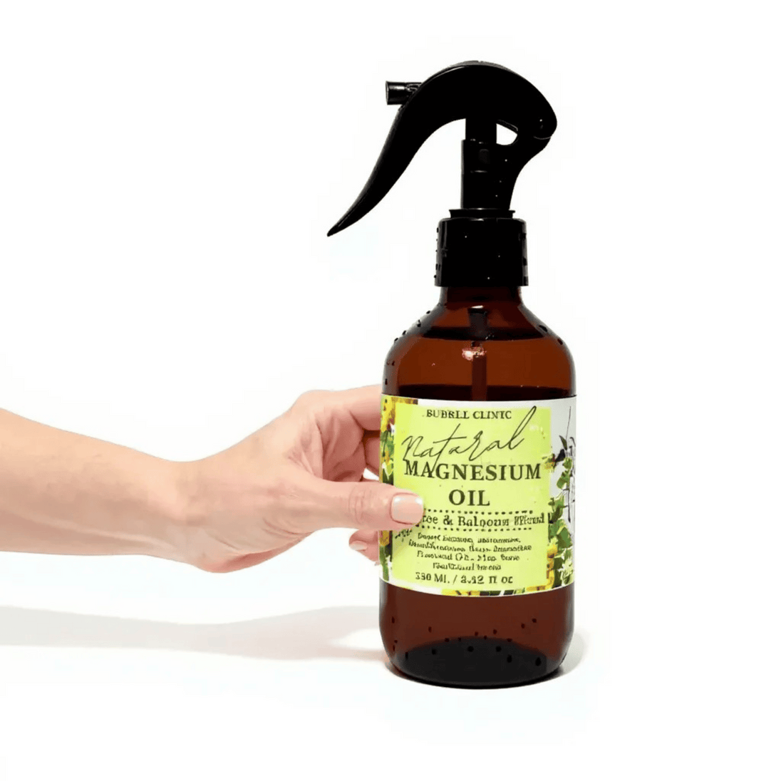 Hand holding a bottle of natural magnesium oil with a label on a white background