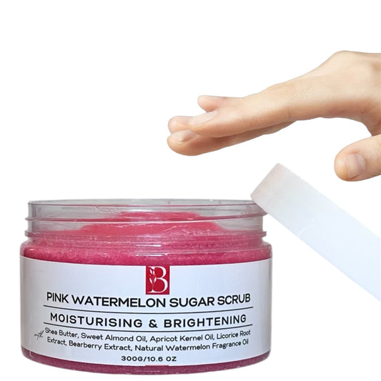 Large tub of Pink Watermelon Brightening Sugar Scrub with a white label and lid on a clean white background. A hand reaches for the tub, showcasing its rich, bright pink exfoliating formula.