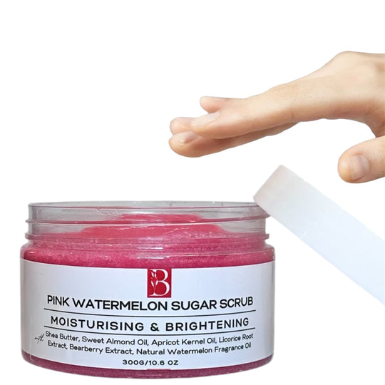 Large tub of Pink Watermelon Brightening Sugar Scrub with a white label and lid on a clean white background. A hand reaches for the tub, showcasing its rich, bright pink exfoliating formula.