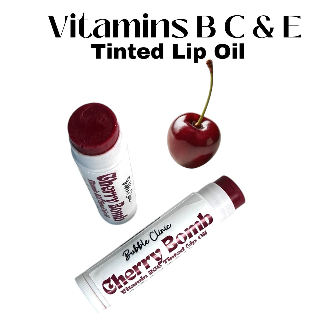 Two open tubes of Cherry Bomb Tinted Lip Oil with rich crimson tint, fresh cherry in the foreground.