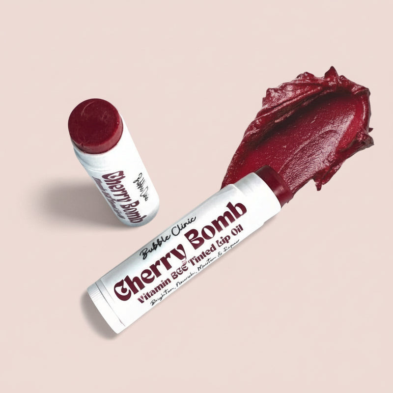 Open Cherry Tinted Vitamin C Lip Balm tubes with a smooth crimson swatch on a white background