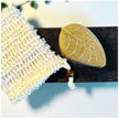 close up of leaf shaped sulphur soap bar with soap saver against white background with botanicals representing natural skincare for acne and rosacea.