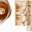 close up of top of soothing goatmilk oats and honey soap with organic pot of honey and sprinkled oats. Organic ingredients for Soothing skin relief.
