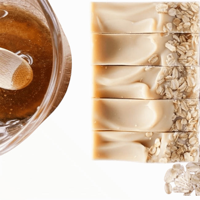 close up of top of soothing goatmilk oats and honey soap with organic pot of honey and sprinkled oats. Organic ingredients for Soothing skin relief.