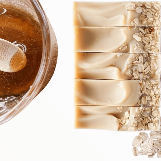 close up of top of soothing goatmilk oats and honey soap with organic pot of honey and sprinkled oats. Organic ingredients for Soothing skin relief.