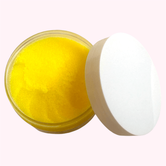 Close-up of natural brightening turmeric scrub in a biodegradable clear jar, featuring vibrant yellow color from organic turmeric, turmeric oil, and licorice extract for glowing skin.