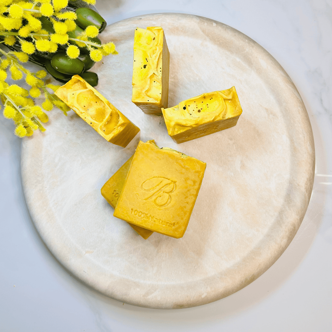 Bright yellow triple turmeric soap bars on a concrete tray with Australian botanicals, featuring organic ingredients and potent turmeric for natural brightening and radiant skin.