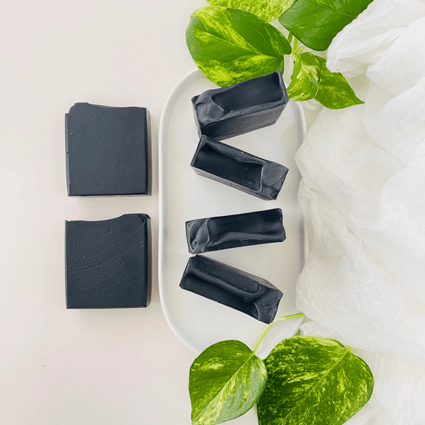 Vibrant black hue detoxifying charcoal soaps. 5 bars with botanicals showcasing all natural soap.