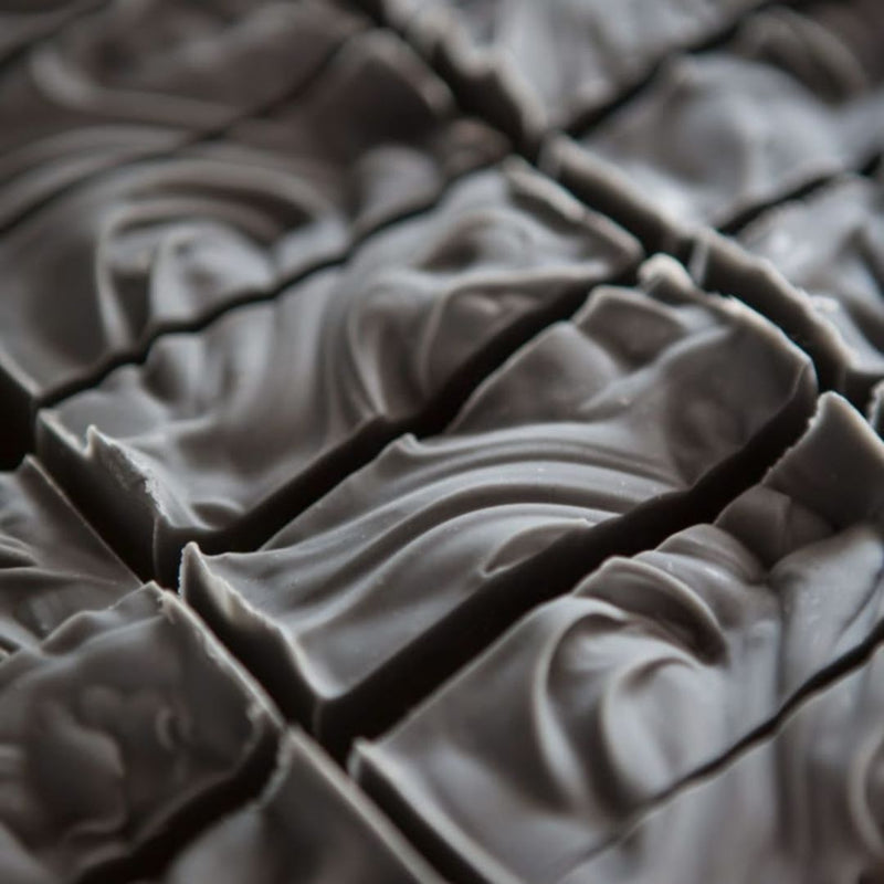 A close-up of activated charcoal swirled, cut bars of soap filling the frame.