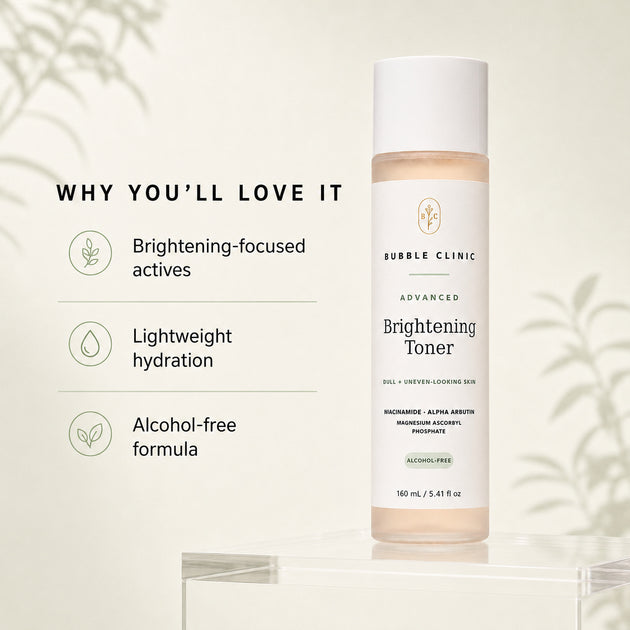 Bubble Clinic Advanced Brightening Toner bottle displayed on a clear acrylic pedestal against a warm cream background with soft leaf shadows. The left side features marketing text reading 'WHY YOU'LL LOVE IT' with bullet points about brightening-focused actives, lightweight hydration, and alcohol-free formula.