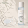 Bubble Clinic Advanced Multi-Acid Blemish Control Toner bottle shown next to a clear petri dish with liquid droplets on a warm beige background with soft leaf shadows.
