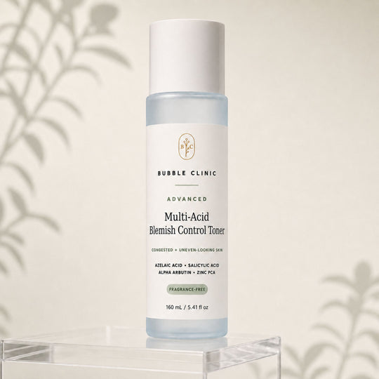 Bubble Clinic Advanced Multi-Acid Blemish Control Toner in a clear bottle with a white cap, displayed on a clear acrylic stand against a warm beige background with soft leaf shadows.