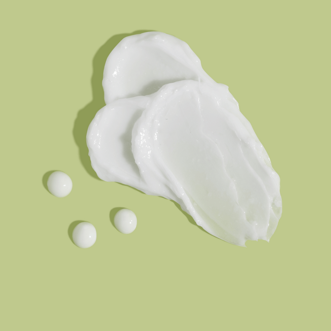 cream swab of azelaic acid 10 percent on a light green background revealing silky creamy texture of the azeluxe lotion for acne.