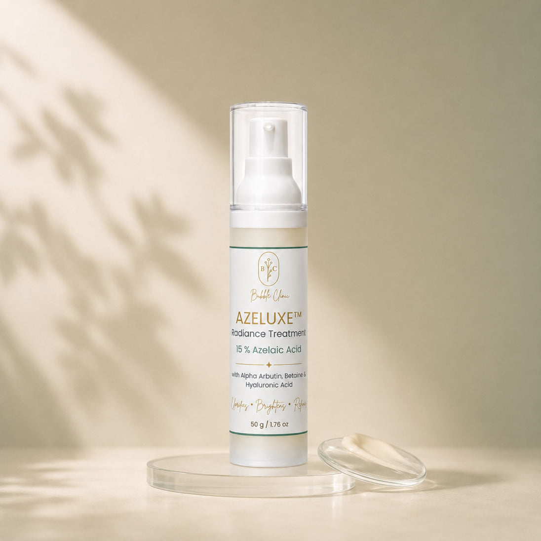A bottle of Azeluxe Radiance Treatment byBubble Clinic on a beige surface with soft leaf shadows. The clear pump bottle is shown with its clear cap off, resting on a clear acrylic stand next to a small clear dish with the cream swatch on it.