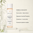 Bubble Clinic Advanced Brightening Toner bottle displayed on a clear acrylic stand with a formula highlights text overlay on a warm off-white background.