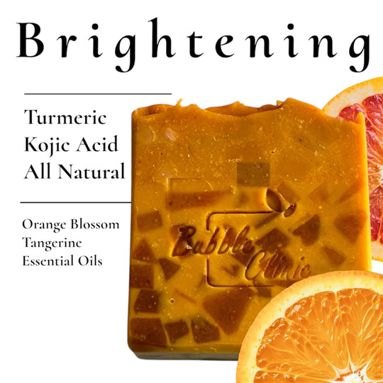 Natural Brightening Soap on white background listing primary ingredients: Turmeric, Kojic Acid, Orange Blossom & Tangerine Essential oil with fresh orange slices highlighting natural ingredients.
