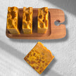 Four Britghtening Turmeric Kojic Acid Soaps, 3 on a rustic wooden tray. Beautiful mosaic design on bright yellow, turmeric enriched soap.