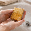 Hands lathering Bubble Clinic Two Tone Turmeric Vitamin C Kojic Acid soap under running water