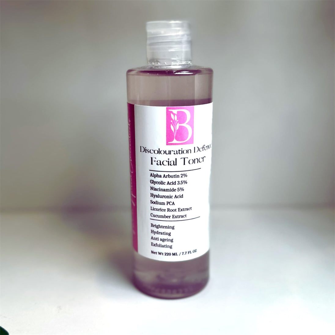 bottle of skin brightening alpha arbutin toner with glycolic acid - against clear background representing natural treatment for dark spots, acne and hyperpigmentation.