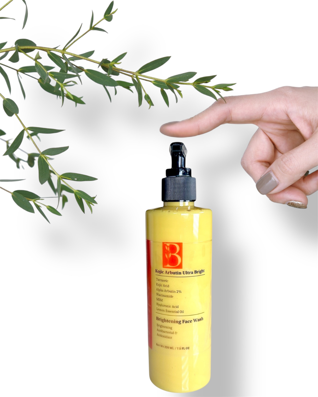 image showing clear pump bottle of turmeric kojic acid face wash with finger about to press the pump and white background with botanicals representing gentle natural brightening skincare for sensitive skin