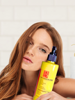 woman affectionately holding bright yellow bottle of turmeric kojic acid face wash with alpha arbutin highlighting gentle brightening cleanser for sensitive skin