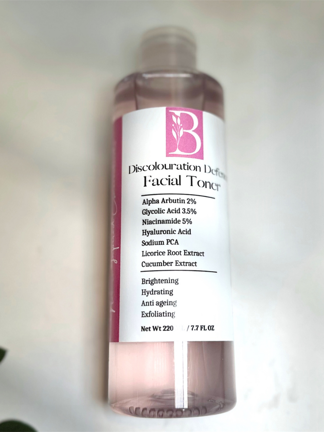 simple top down view of natural brightening toner with alpha arbutin and glycolic acid on white surface representing natural clean beauty rituals 