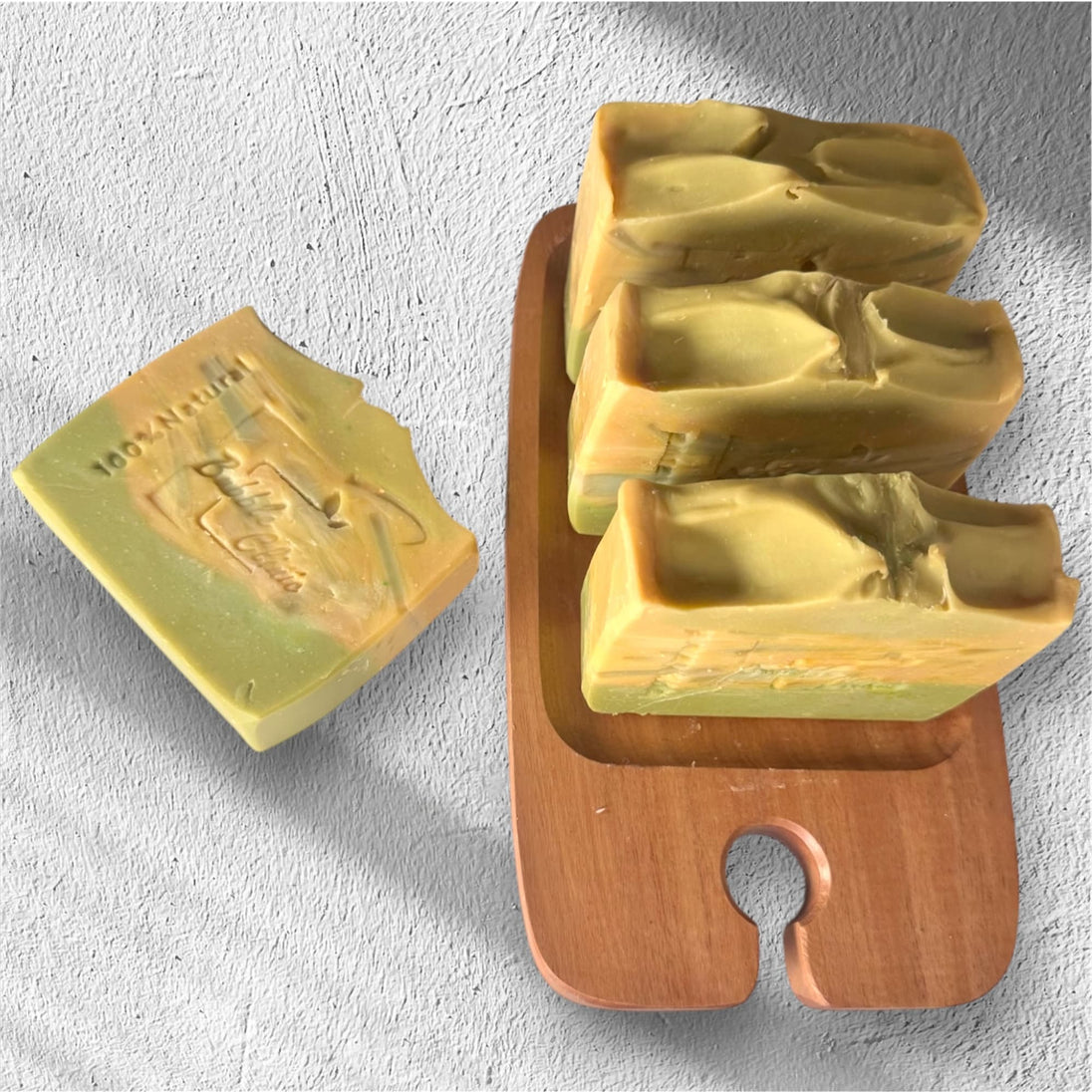 Four bars of Turmeric, Kojic Acid & Alpha Arbutin Brightening Soap on a rustic wooden tray, highlighting its natural formula for glowing skin.