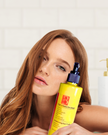 white background with woman affectionately holding bright yellow bottle of turmeric kojic acid face wash with alpha arbutin highlighting gentle brightening cleanser for sensitive skin