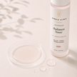 Advanced Radiance Toner lightweight formula texture beside the muted-blush-labelled frosted bottle