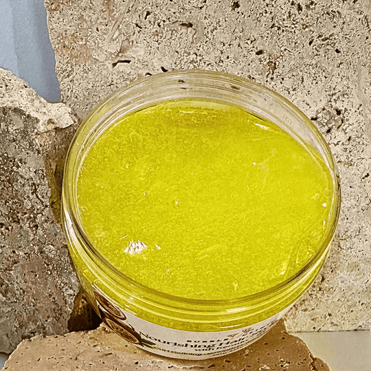 open container of passionfruit kerating hair gel revealing clear, bright yellow gel against natural stone background.