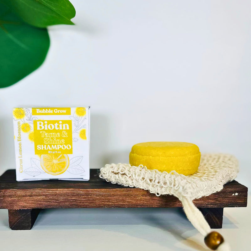 Turmeric shampoo bar on a wooden draining tray with botanicals