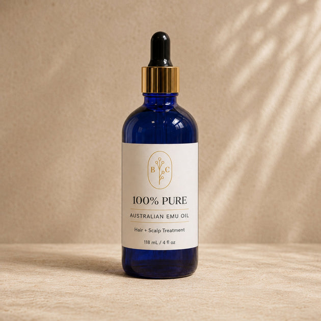 100% Pure Australian Emu Oil Hair and Scalp Treatment clean studio image blue cobalt bottle styled on warm beige background.