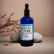 blue glass dropper bottle 100% natural organic Australian Emu Oil organic botanicals in background representing pure organic Australian skincare.