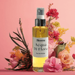 Bottle of 'Acqua Di Flora' perfume surrounded by flowers on a pink background