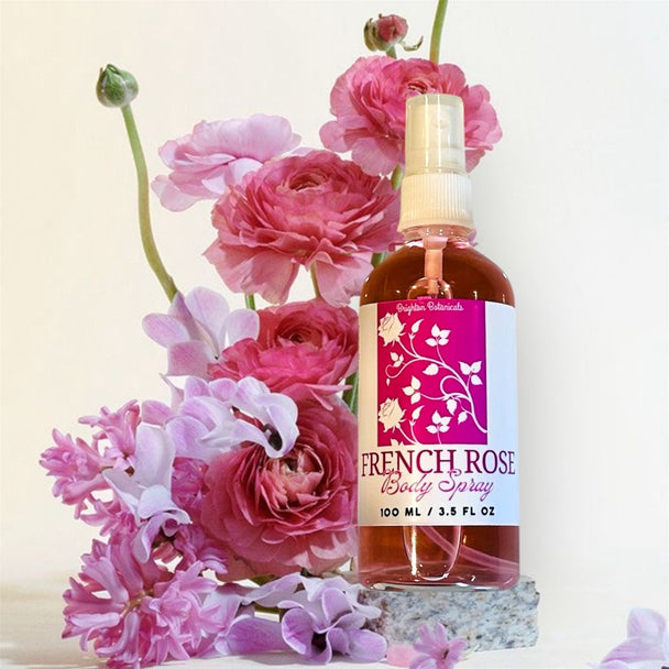 Close-up of a glass bottle of French Rose Fragrance Body Mist with a bouquet of roses in the background, highlighting its romantic and elegant scent.

