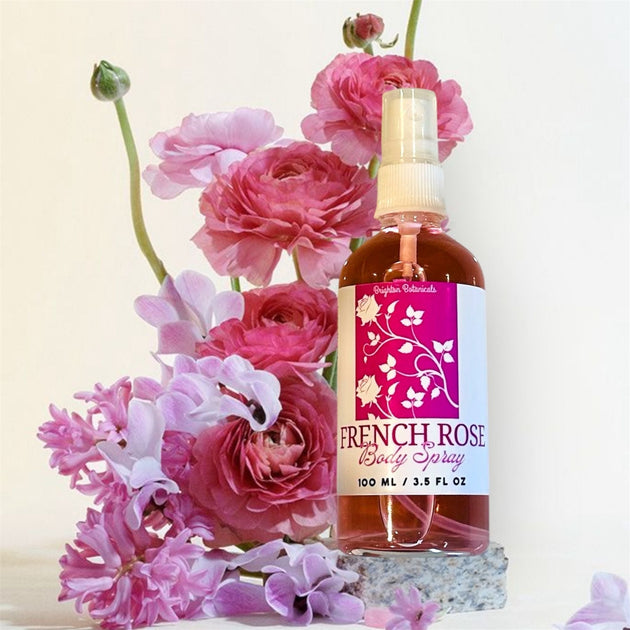 Close-up of a glass bottle of French Rose Fragrance Body Mist with a bouquet of roses in the background, highlighting its romantic and elegant scent.

