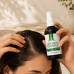 Hair and scalp serum bottle held beside a cleanly parted scalp