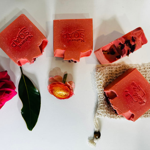 Top view of natural, organic, Himalayan Rhubarb essential oils soap with organic green leaf, roses and soap saver against bright white background representing the best of Australian natural skincare for sensitive skin.