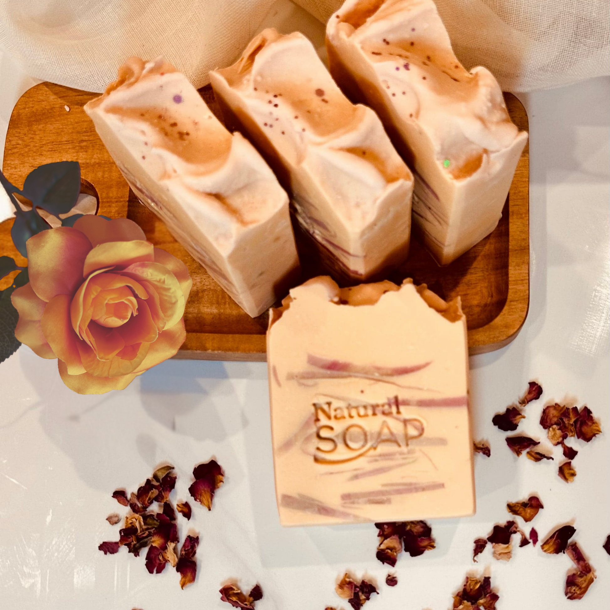 Kojic acid soap bars on organic wooden tray with organic rose and petals representing natural organic ingredients and rose fragrance.