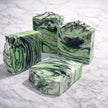 Green and black marbled kojic peppermint soap bars with activated charcoal on a marble surface representing best natural brightening soaps Australian made.