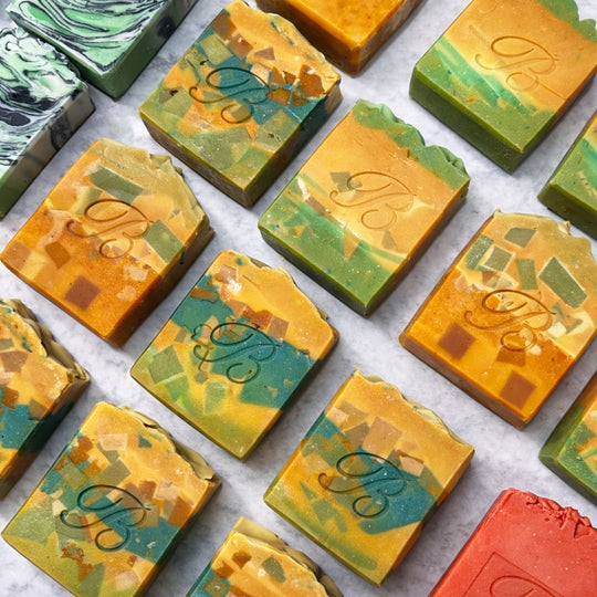 Assorted Turmeric Kojic Acid brightening soap bars with a brand logo on a white background representing best natural brightening skincare Australian Made