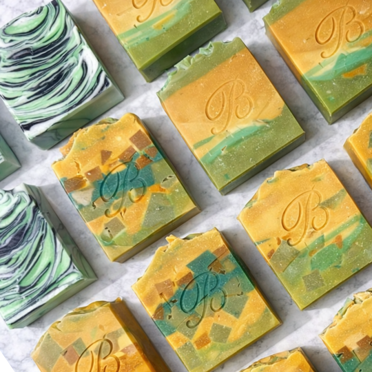 Assorted Turmeric Kojic Acid brightening soap bars with a brand logo on a white background representing best natural brightening skincare Australian Made