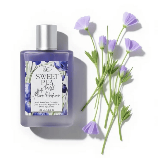 luxury hair perfume with sweet pea essential oil, argan oil, keratin and olive squalane with floral labe and text Anti Frizz Hair perfume alongside sweet pea flowers on white background
