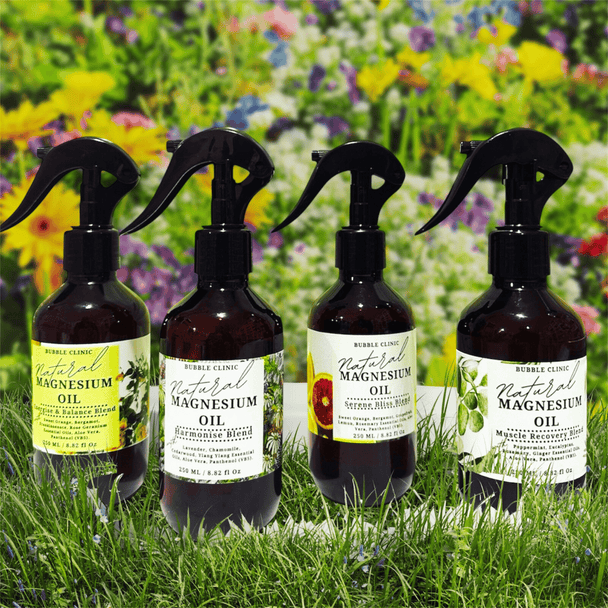 Four bottles of magnesium oil with labels on grass and flowers background each with an exclusive aromatherapy blend of premium essential oils.