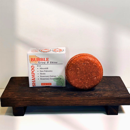dark organge, round natural, sulfate free shampoo bar with minoxidil pictured with package box on rustic wooden tray representing natural, sulfate free haircare made in Australia.