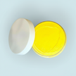 Open container of yellow natural turmeric cream on a light green background