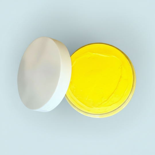 Open container of yellow natural turmeric cream on a light green background